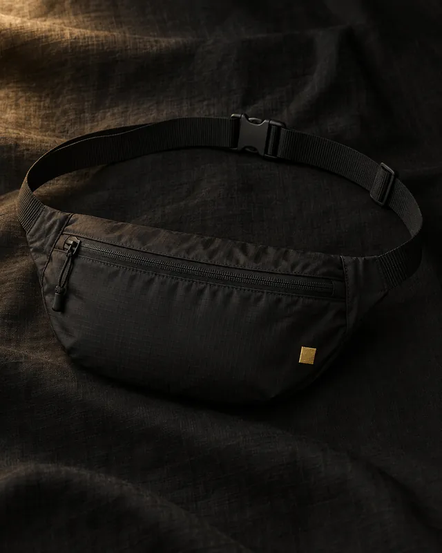 Sac banane noir fin avec une étiquette carrée dorée, vue principale.